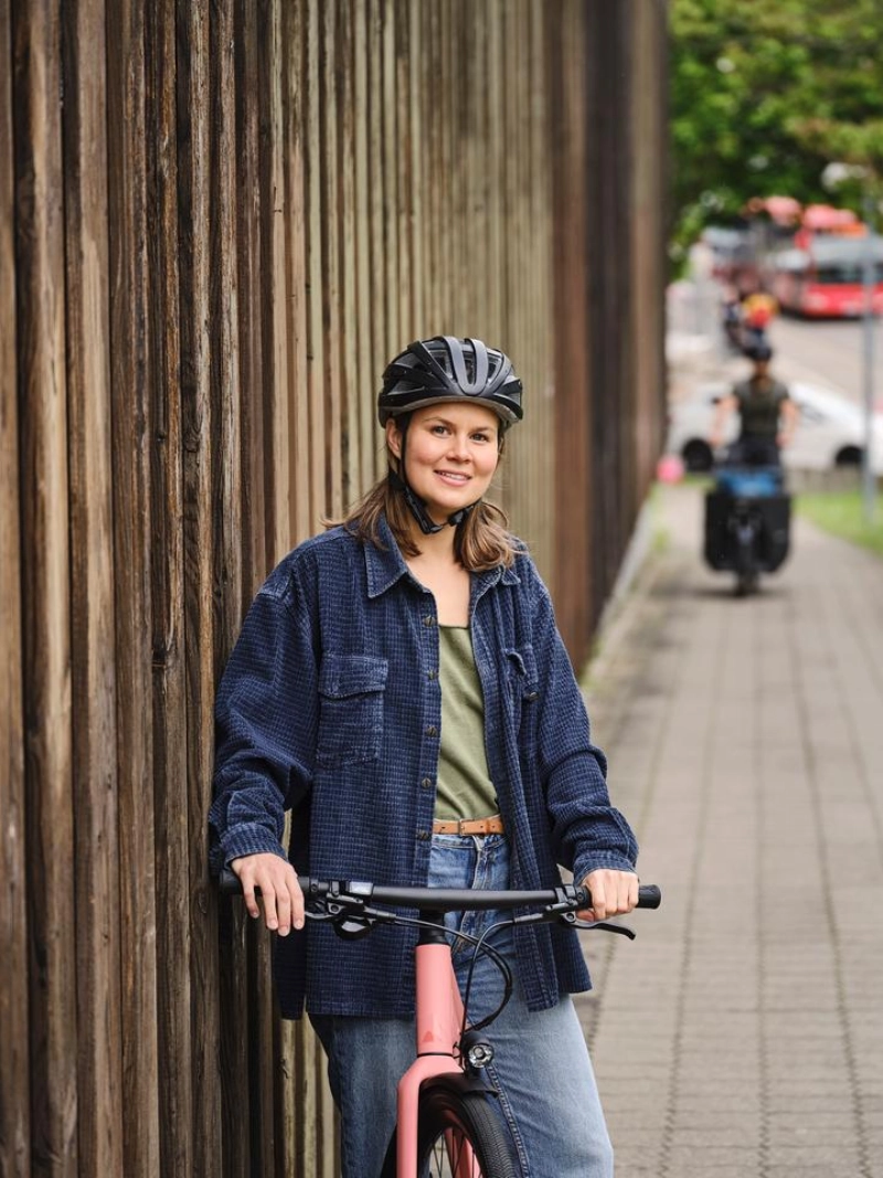 JobRadlerin wartet lächelnd auf Person mit Lastenrad JobRadlerin wartet lächelnd auf Person mit Lastenrad